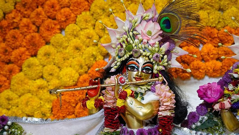 An idol of Lord Krishna adorned with a white dress and marigold flowers