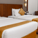 Twin bed room at Featherlite Evoma Hotel with beds dressed in white and gold linen, wooden headboards and warm ambient lighting nearby.