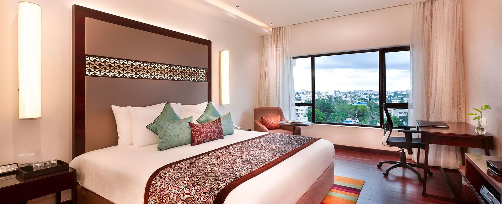 A spacious, well-lit hotel room at GRT Grand Chennai with a king sized bed and a large window overlooking the city. - Best hotel near U.S Consulate Chennai 