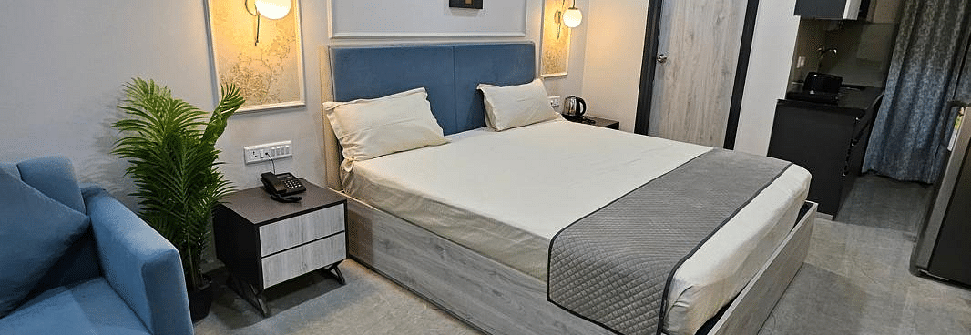 Diagonal view of a spacious room with a large bed, bedside lamps on both sides, and the bedroom at Urban Suites by BluSalzz, Jaipur.