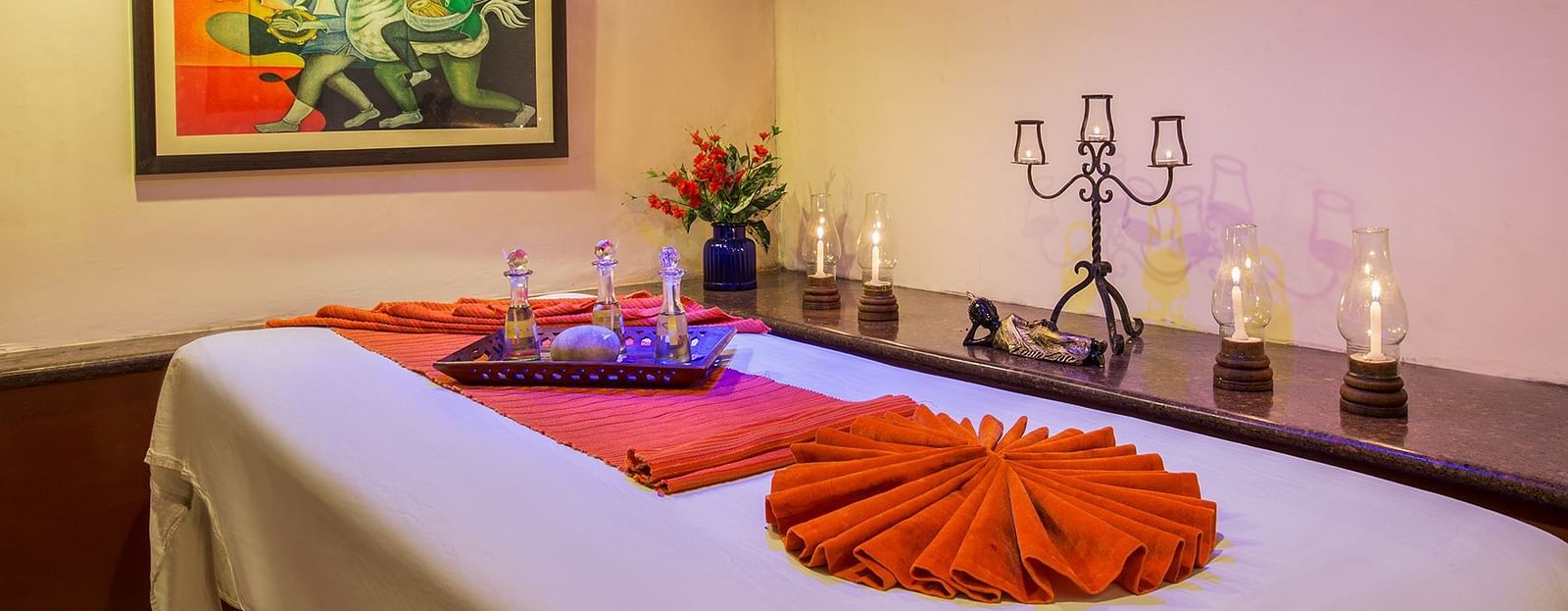 A spa table, candles beside it and a frame on the wall in a treatment room at our Spa in Nainital