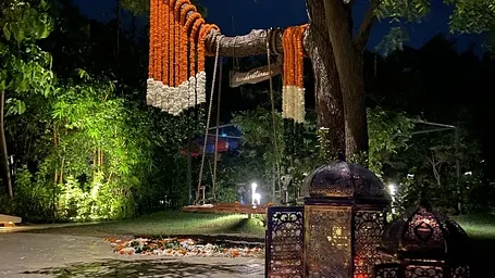 Outdoor space at night with hanging decor, lanterns, and trees lit up at Karma Chalets. 