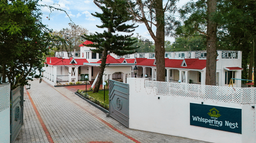 The entrance gate of MGM Whispering Nest with a view to the main buildings amidst the trees