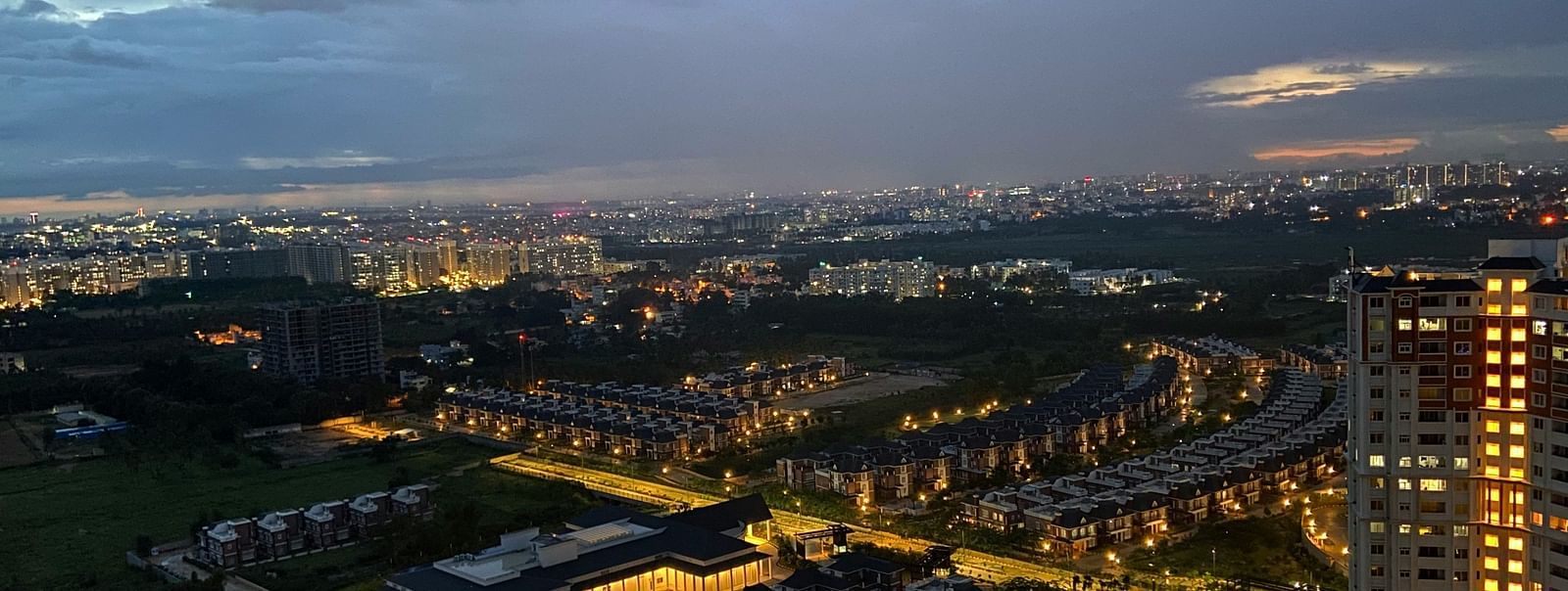 an aerial view of Bangalore in the evening with dark clouds above 
