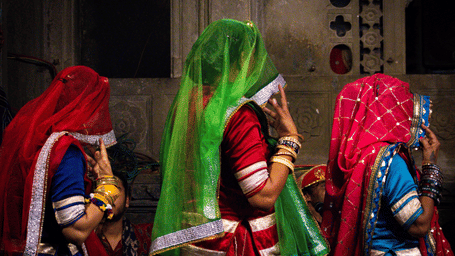 Rajasthani folk dancers dressed in colourful traditional attire performing a cultural dance during an evening celebration.