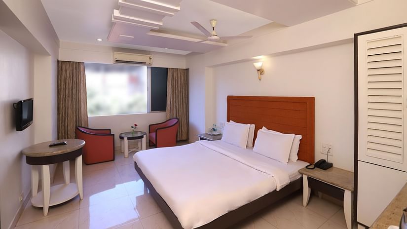 hotel room at Hotel Kohinoor Highway, Dapoli featuring a plush bed, contemporary decor, seating area by the window, and soft natural lighting throughout