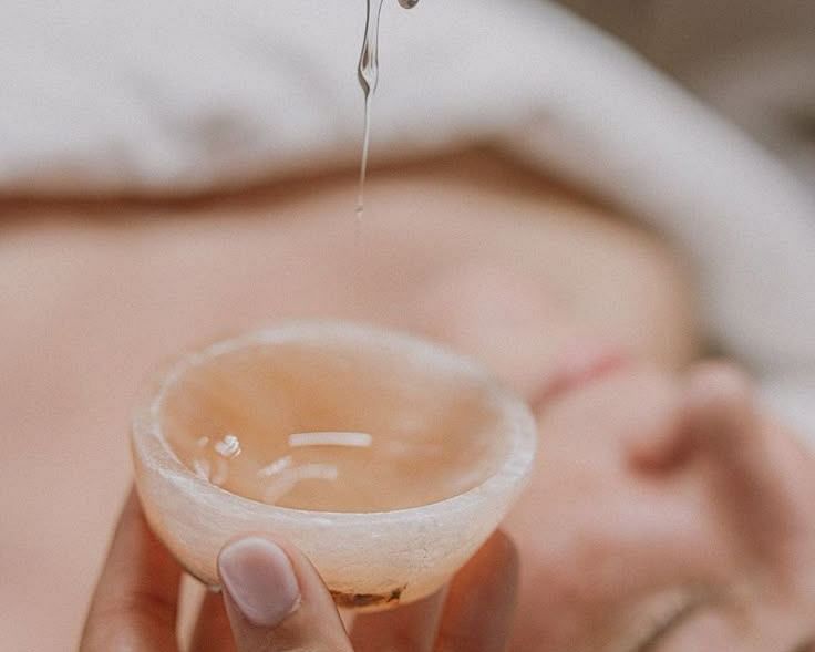 A close-up of liquid being poured from one glass container into another, possibly part of a beauty treatment.