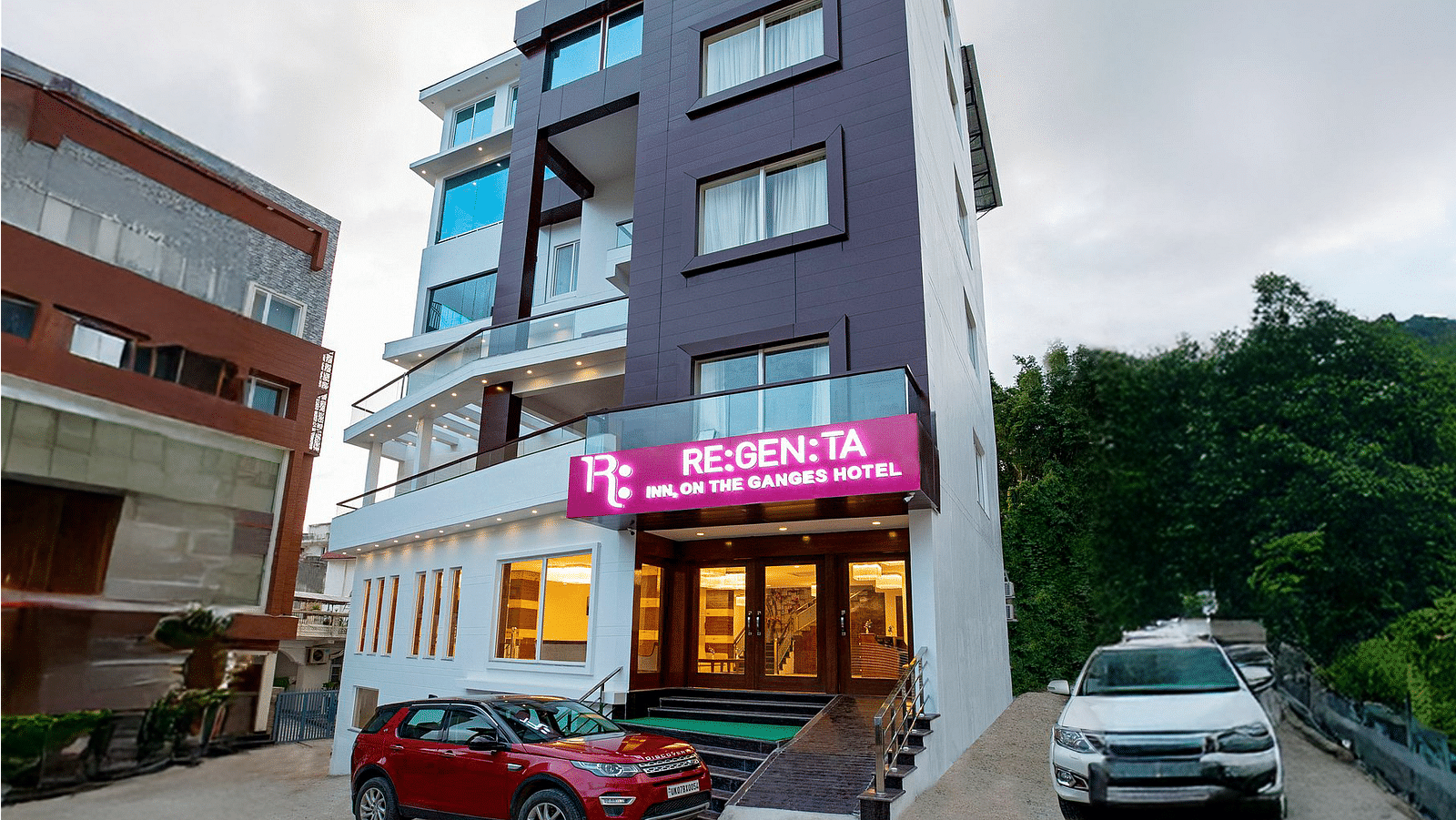 A wind angle shot of Regenta Inn DLS with a lush green hilly region in the background.