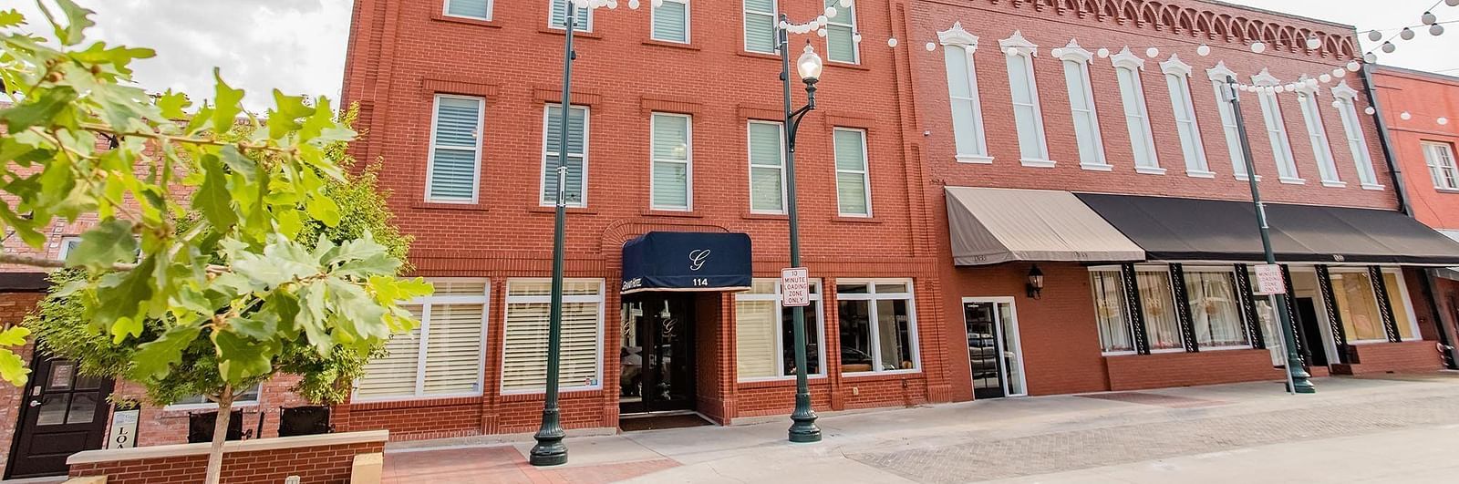 The front view of the Grand Hotel & Ballroom, Mckinney showcasing its historic red-brick building and elegant design on a bright day.