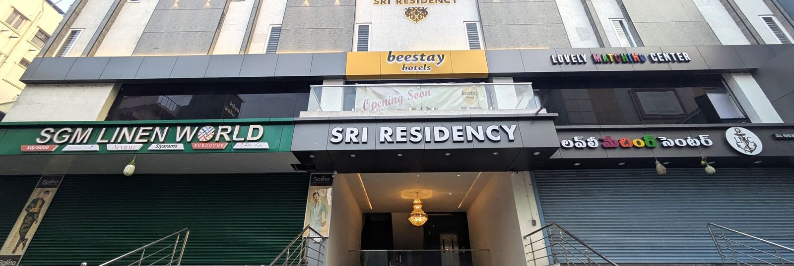 Facade view with signage and entrance with stairs at Beestay Hotels, Rajahmundry.