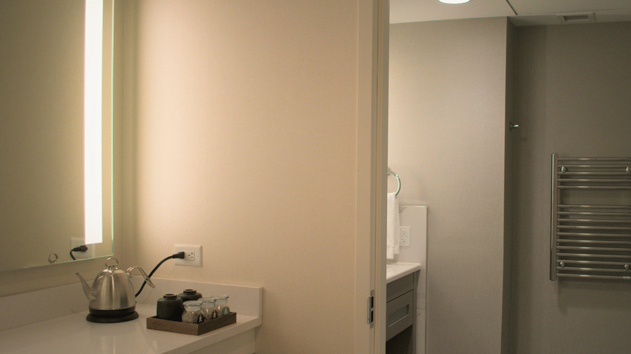 Lakeview King Room at YO1 Longevity & Health Resorts featuring a counter with an electric kettle and tea set, leading into a bathroom with a heated towel rack
