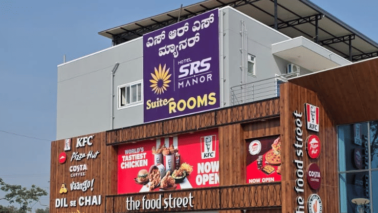 Commercial building entrance with storefronts, signage and a paved pedestrian area.