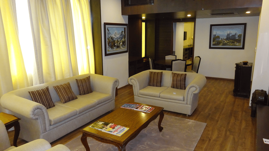 A spacious living room with modern sectional sofa, wooden coffee table, and elegant decor showcasing luxurious suites in Lucknow - Clarks Avadh, Lucknow