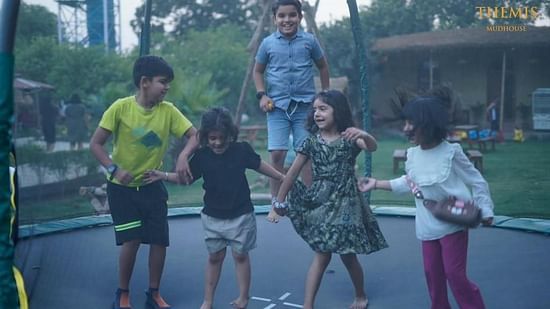 Kids juping on a trampoline at inflated trampoline surrounded by trees at Themis Mudhouse - A Nature's Retreat Resort & Wellness