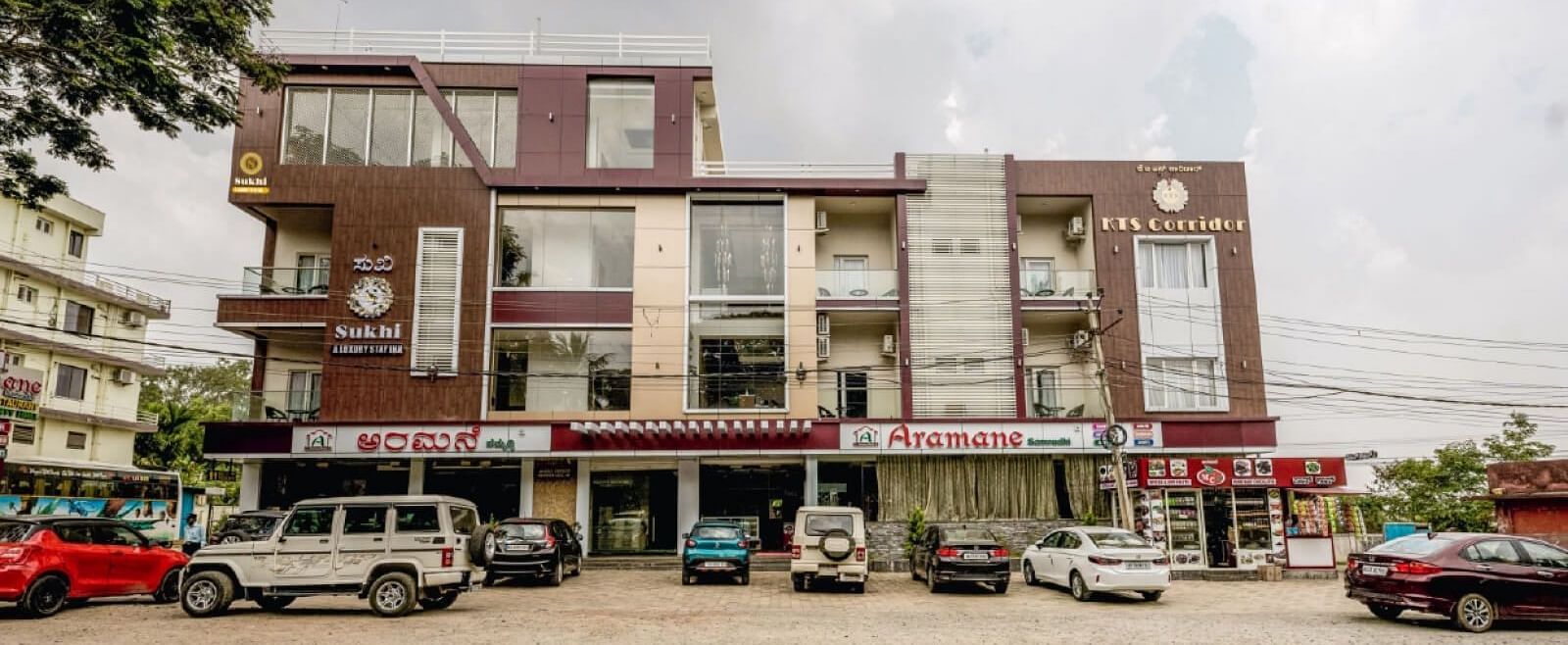 Facade image of Sukhi - A Luxury Stay Inn, Chikkamagaluru with several vehicles parked in the front.
