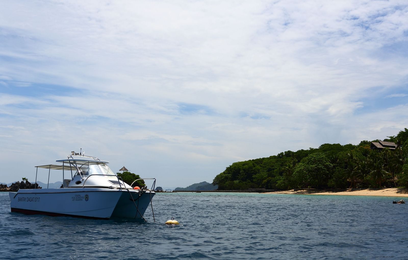 Speedboat anchored in calm blue waters with lush island backdrop.