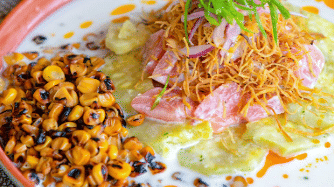 Close-up of a seafood dish topped with greens and toasted corn in a shallow bowl at Lamari Siargao.