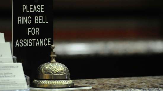 Service bell on a reception counter with a sign requesting assistance.