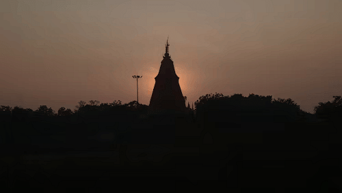 Silhouette of a temple structure at dusk, framed against a fading sky.