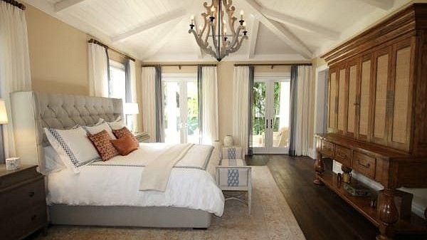 A bedroom interior with large bed and chandelier.