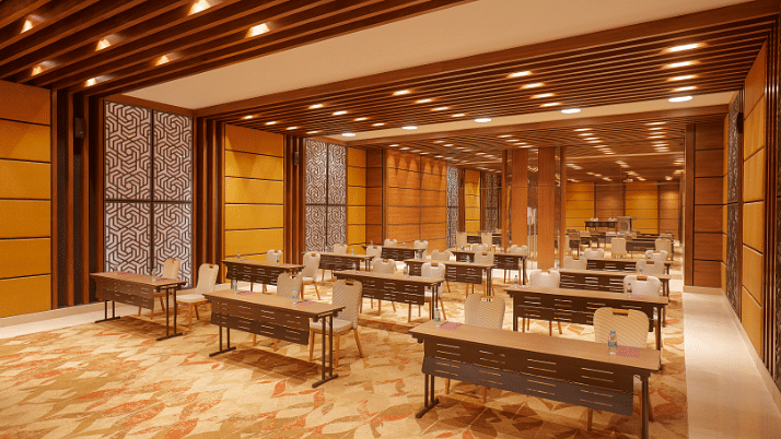 A side angle view of the Premier Banquet Hall at Residency Tower, Chennai, showcasing a royal interior design. The room features elegant decor with rich colors and intricate details. Classroom-style seating is arranged with tables and chairs, creating an i