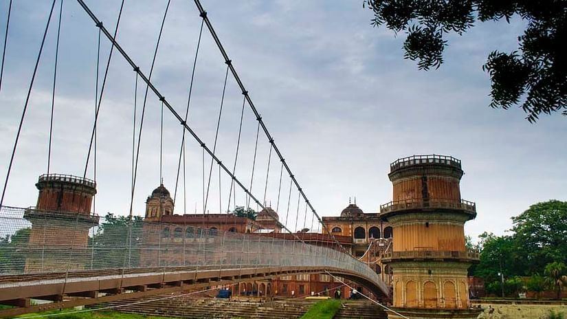 A hanging bridge leading to the Sheesh Mahal with greenery at the bottom