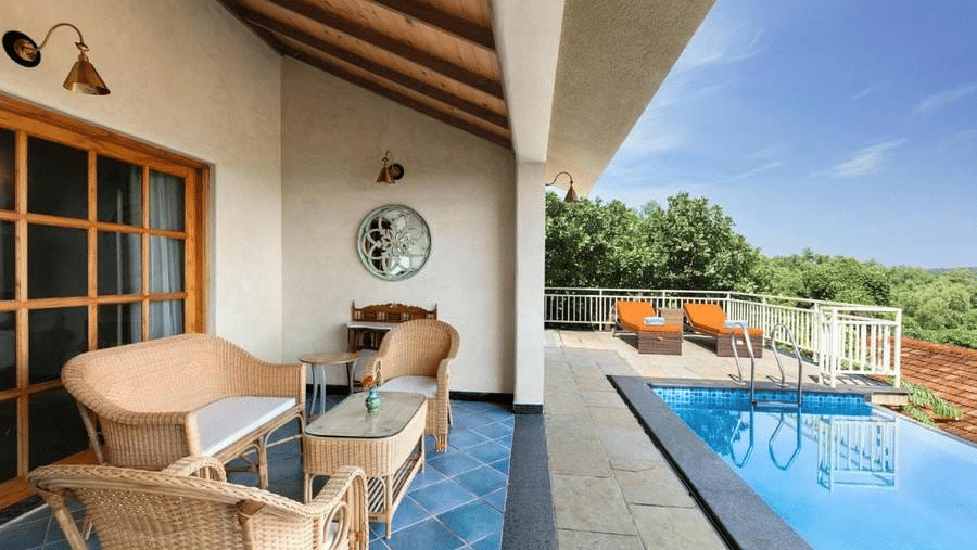 A common seating area with a coffee table in front of it overlooking the infinity pool at the Presidential Suite -  Golden Tulip Goa Mandrem
