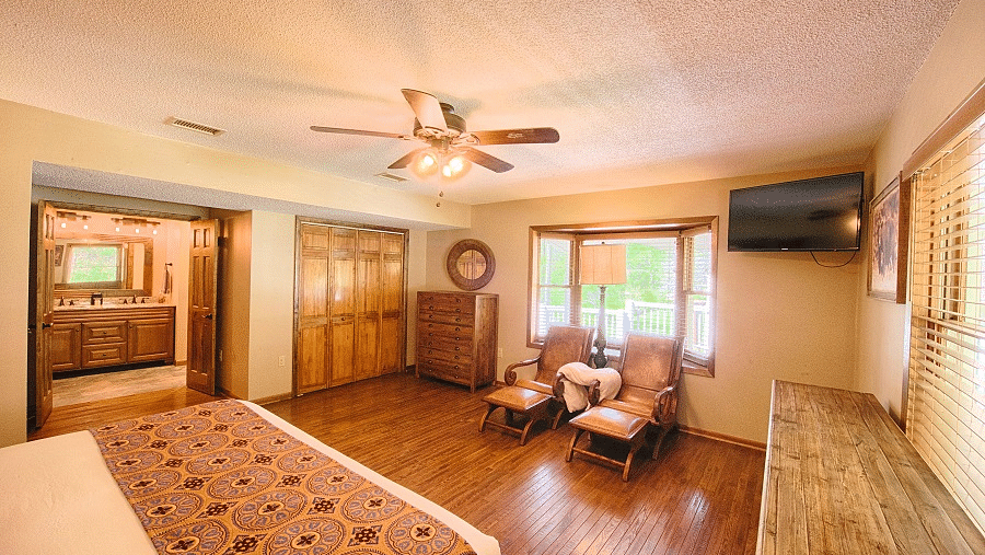 corner view of a beautiful room with a double bed and reclining arm chairs with ceiling fan in the middle of the room - Historic Tapoco Lodge