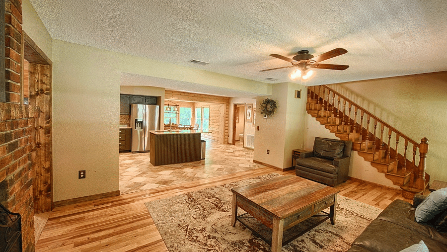 a living area with a brown sofa set along with a ceiling fan and a stairway leading to the upper level - Historic Tapoco Lodge