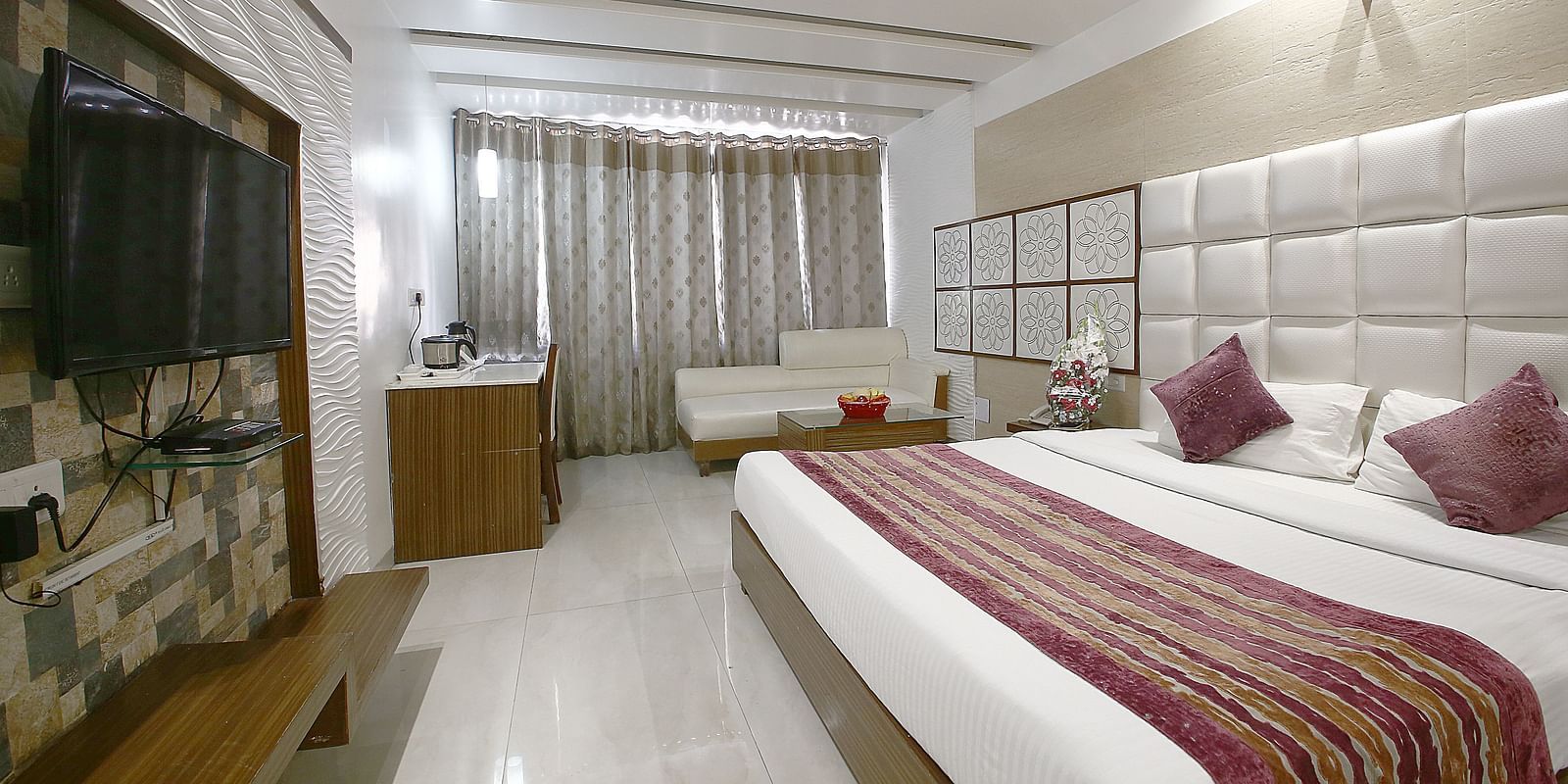 A sophisticated hotel room with plush bedding, a cosy seating area, and contemporary aesthetics - Hotel Emerald, Chandigarh