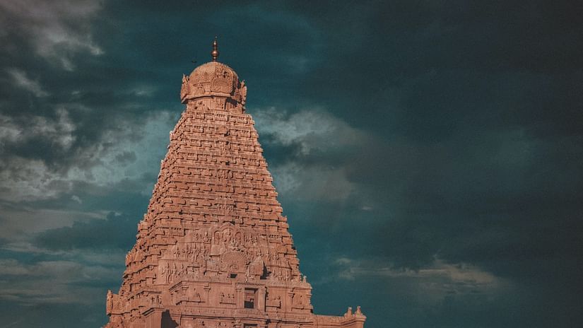 A hindu temple with intricate architecture outside on the roof as seen from a distance.