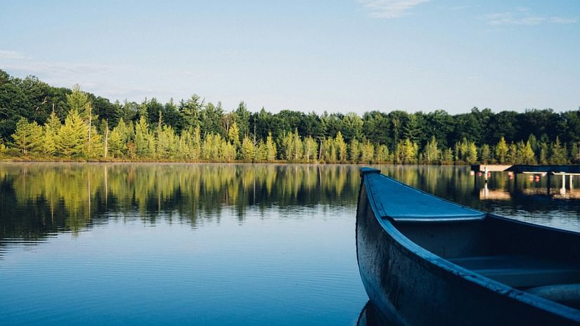 an overview of a lake with A boat in the foreground and forest cover in the background