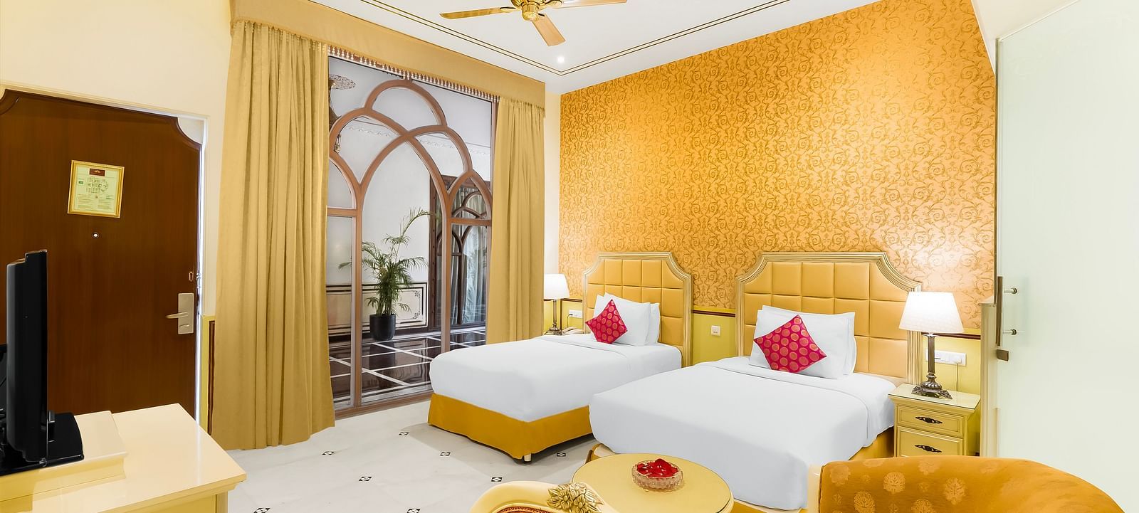 An overview of a room with two single beds, a chair and ceiling fan in view - Rajasthali Resort & Spa, Jaipur.
