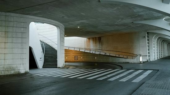 An image of a parking area featuring a staircase, curved road, and zebra crossing