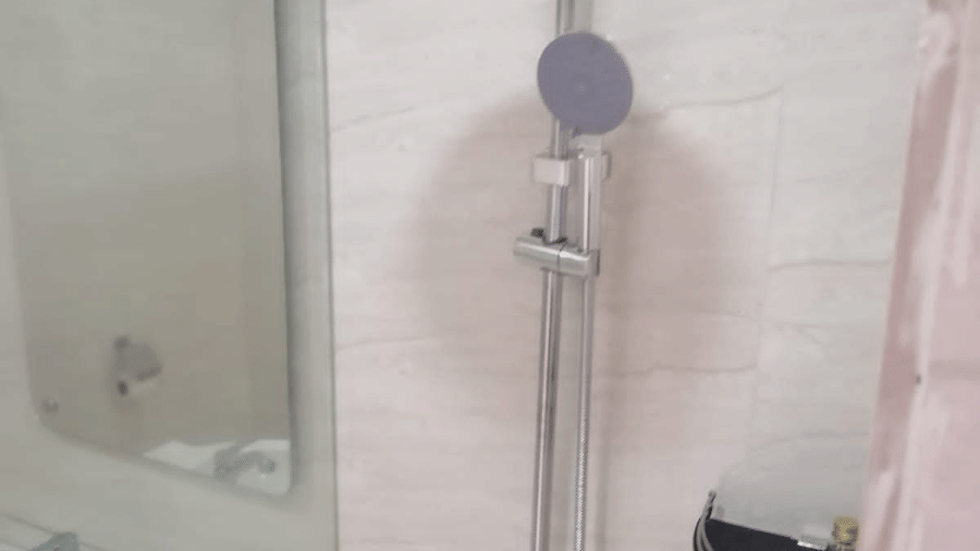 A clean, modern bathroom featuring a chrome rainfall shower head and white tiled walls in a minimalist style at Apartel by Aarin, Oragadam.