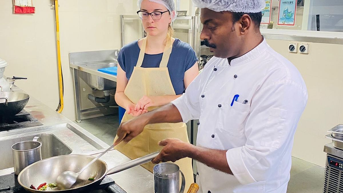 Cookery session with the chef and four assistants standing around a table filled with cooking equipment and ingredients