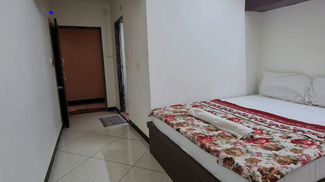 Simple and well-maintained room interior with bed and entrance view at Dream Vision Guest House, Diu.