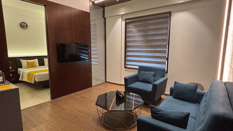 The separate living room of the Premier Suite with teal-coloured couch set placed in front of the wall-mounted television at SRS Suites, Koramangala.
