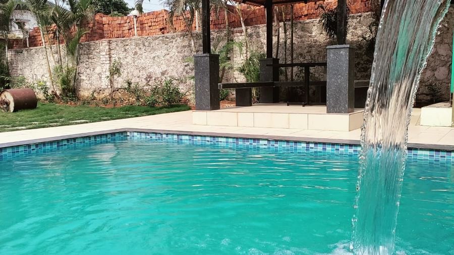 Swimming pool at Mountview Resort in Lonavala, with waterfall feature and shaded gazebo for relaxation.