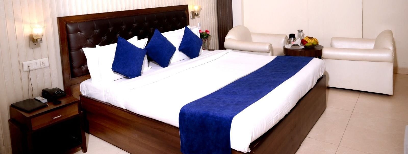 Elegant white-themed room at Hotel Diamond Inn, Chandigarh with deep blue accents and a cushioned seating area.