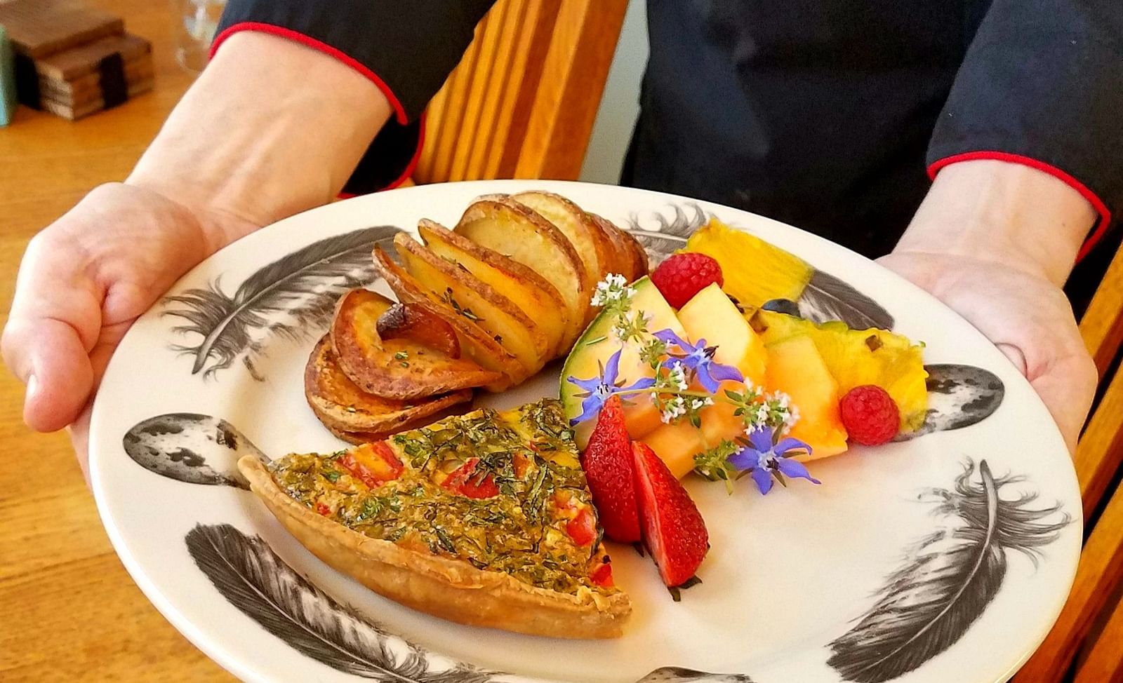 A staff member presenting a beautifully plated meal - Brewery Gulch Inn & Spa