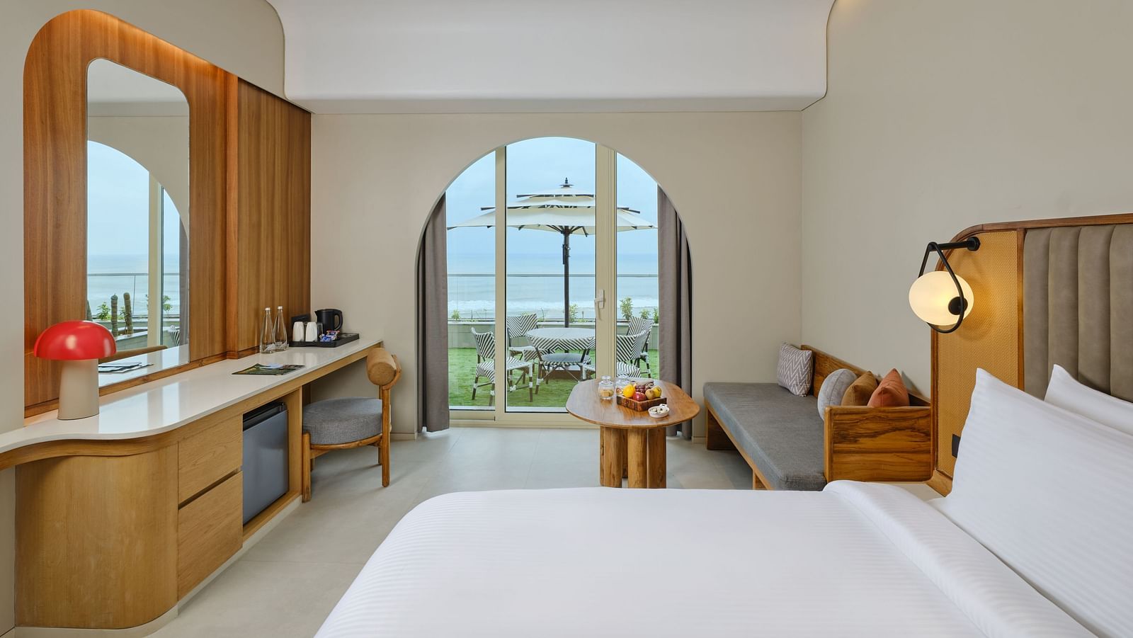 Image of Premium Room at Swosti Premium Beach Resort in Puri featuring a plush bed and a couch with a coffee table next to the doorway to the outdoor sitting space with the majestic view of the sea