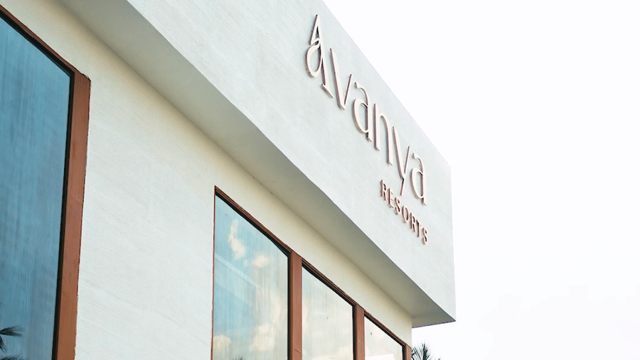 A low-angle shot of a white building with large windows and the resort's name visible on the upper facade at Avanya Resorts N Retreat.