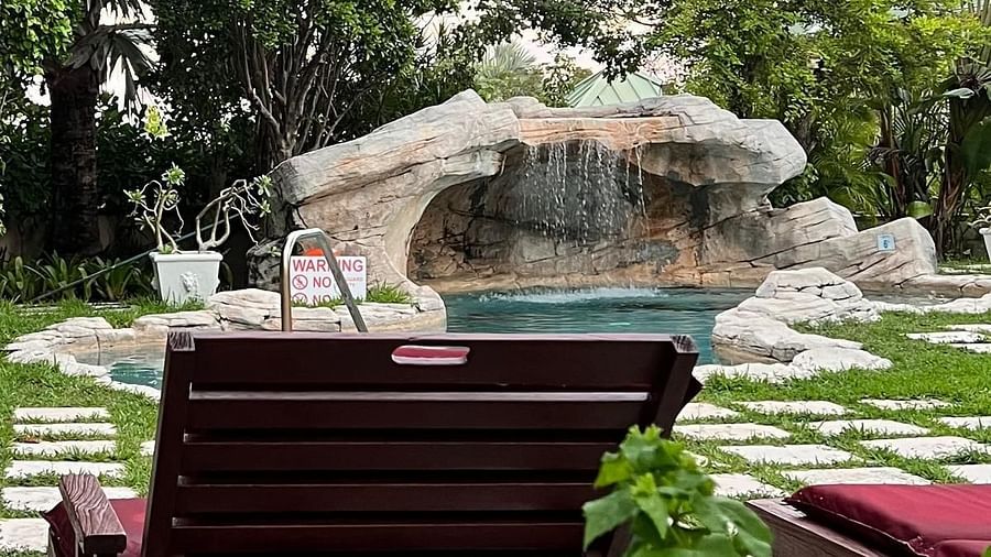Lounge chair facing a stone-lined pool with trees in the background | A Stone's Throw Away