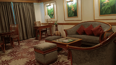 A living room featuring a floral-patterned carpet, grey upholstered seating, wooden furniture, and tropical-themed wall art with warm lighting - Pride Premier Pune