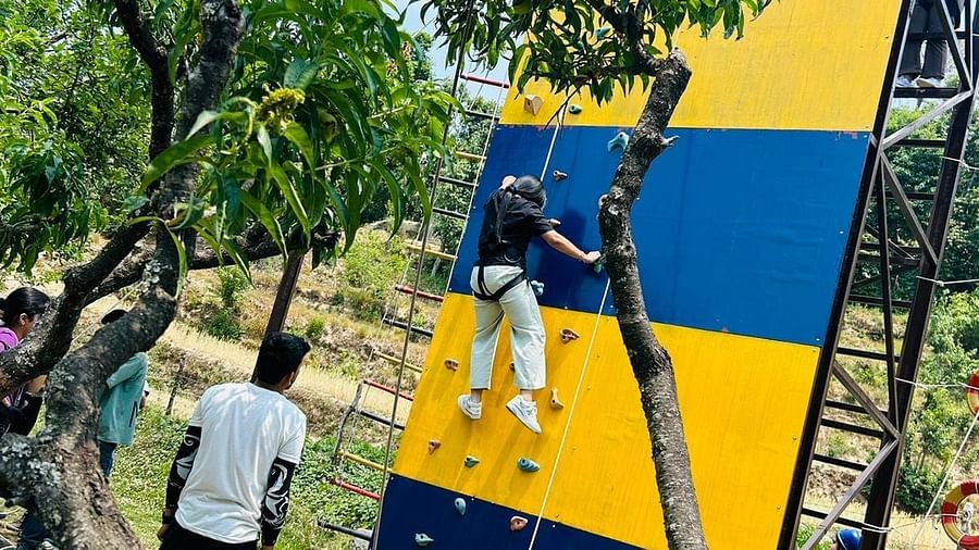 A vibrant climbing wall with colorful panels, attracting adventure seekers and families. People are visible nearby - Digantaa Resort in Mukteshwar