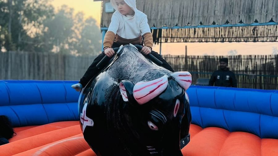 A child on a mechanical bull ride at inflated trampoline surrounded by trees at Themis Mudhouse - A Nature's Retreat Resort & Wellness