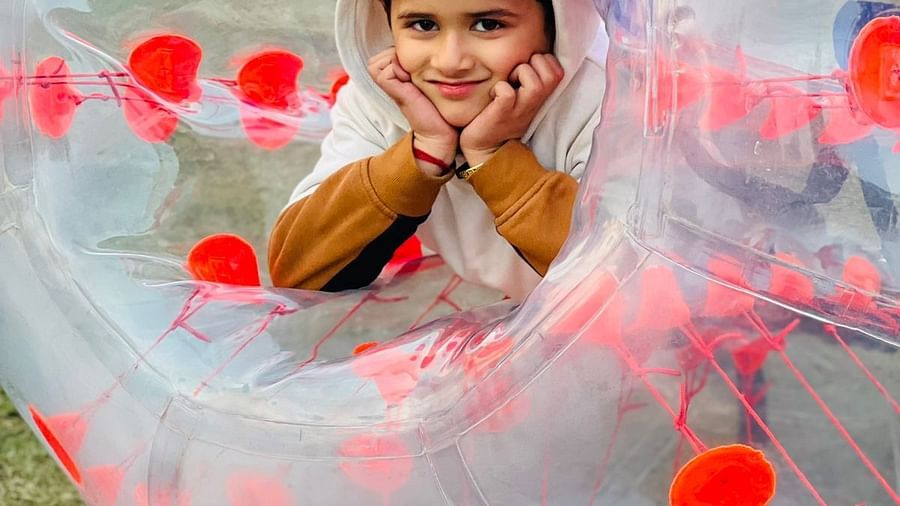 A child peeking out from a zorbing ball at Themis Mudhouse - A Nature's Retreat Resort & Wellness