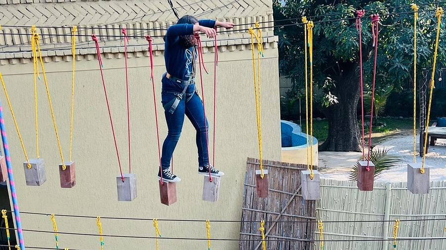 A person on a rope course at inflated trampoline surrounded by trees at Themis Mudhouse - A Nature's Retreat Resort & Wellness