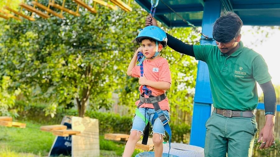 A child enjoying tyre course at inflated trampoline surrounded by trees at Themis Mudhouse - A Nature's Retreat Resort & Wellness